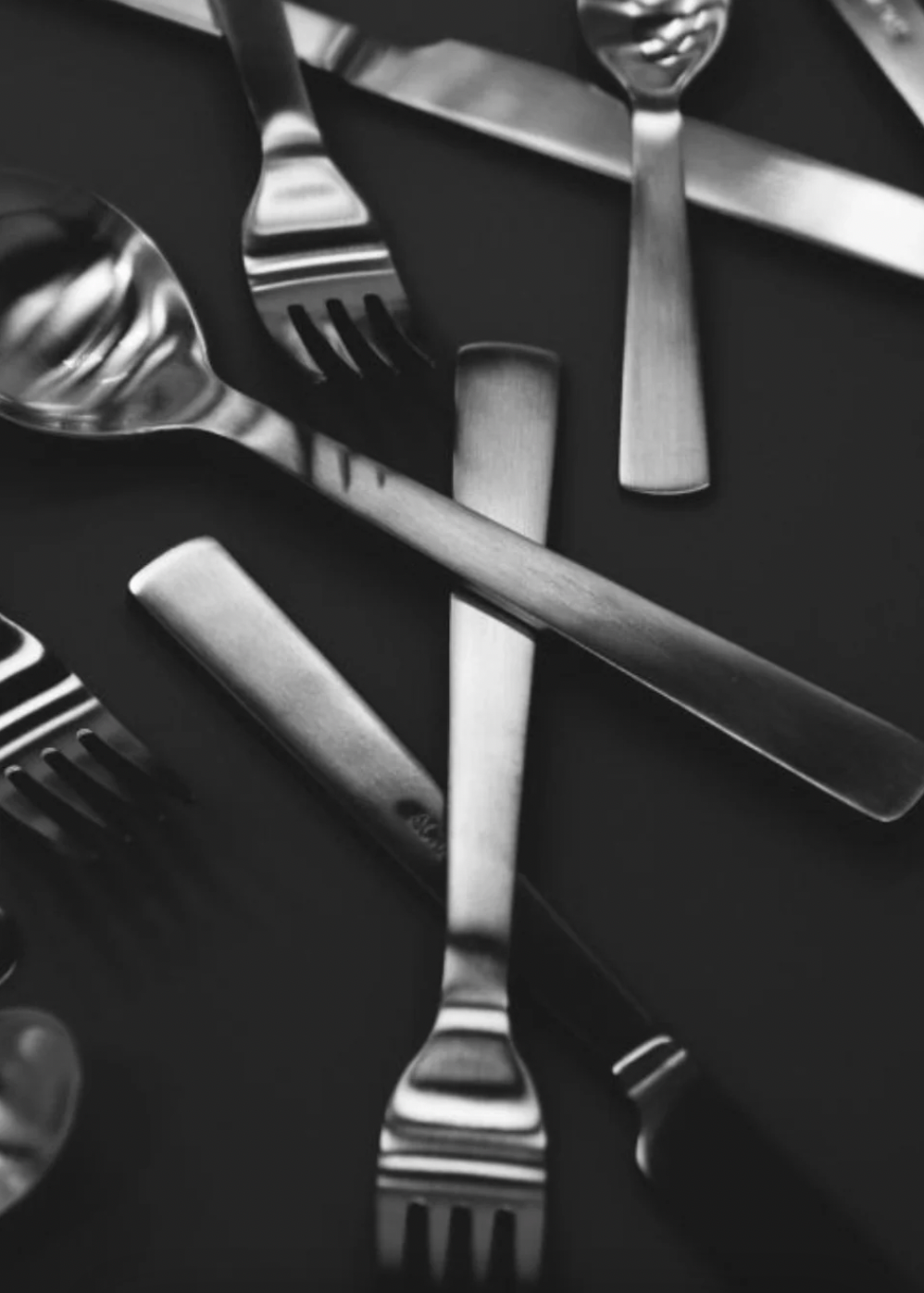 Silverware including forks and knives on a dark surface