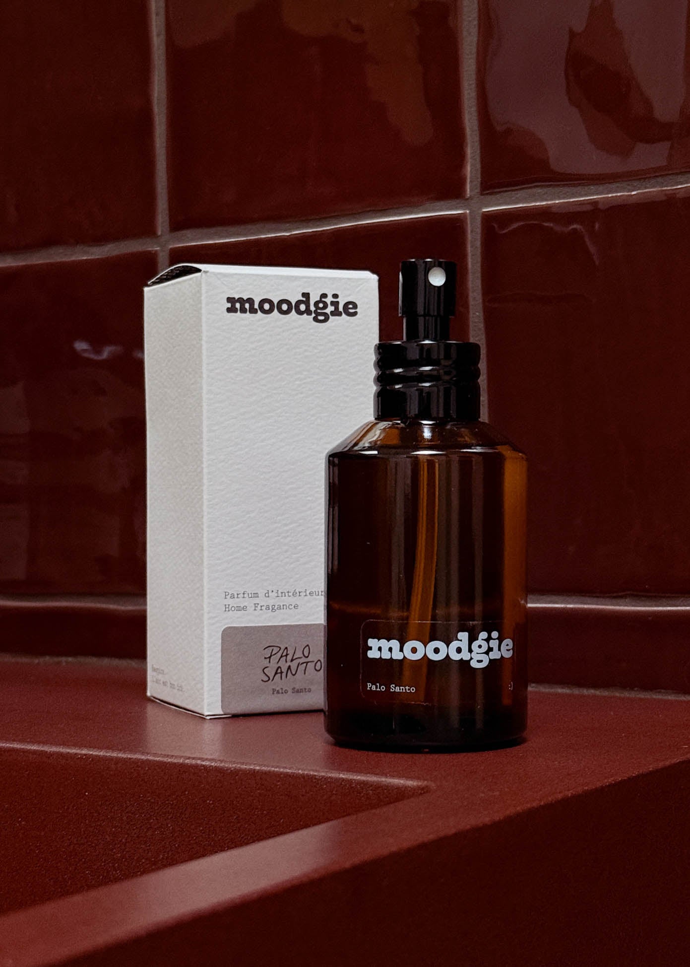 Brown 'moodgie' perfume bottle and box on a red tiled surface