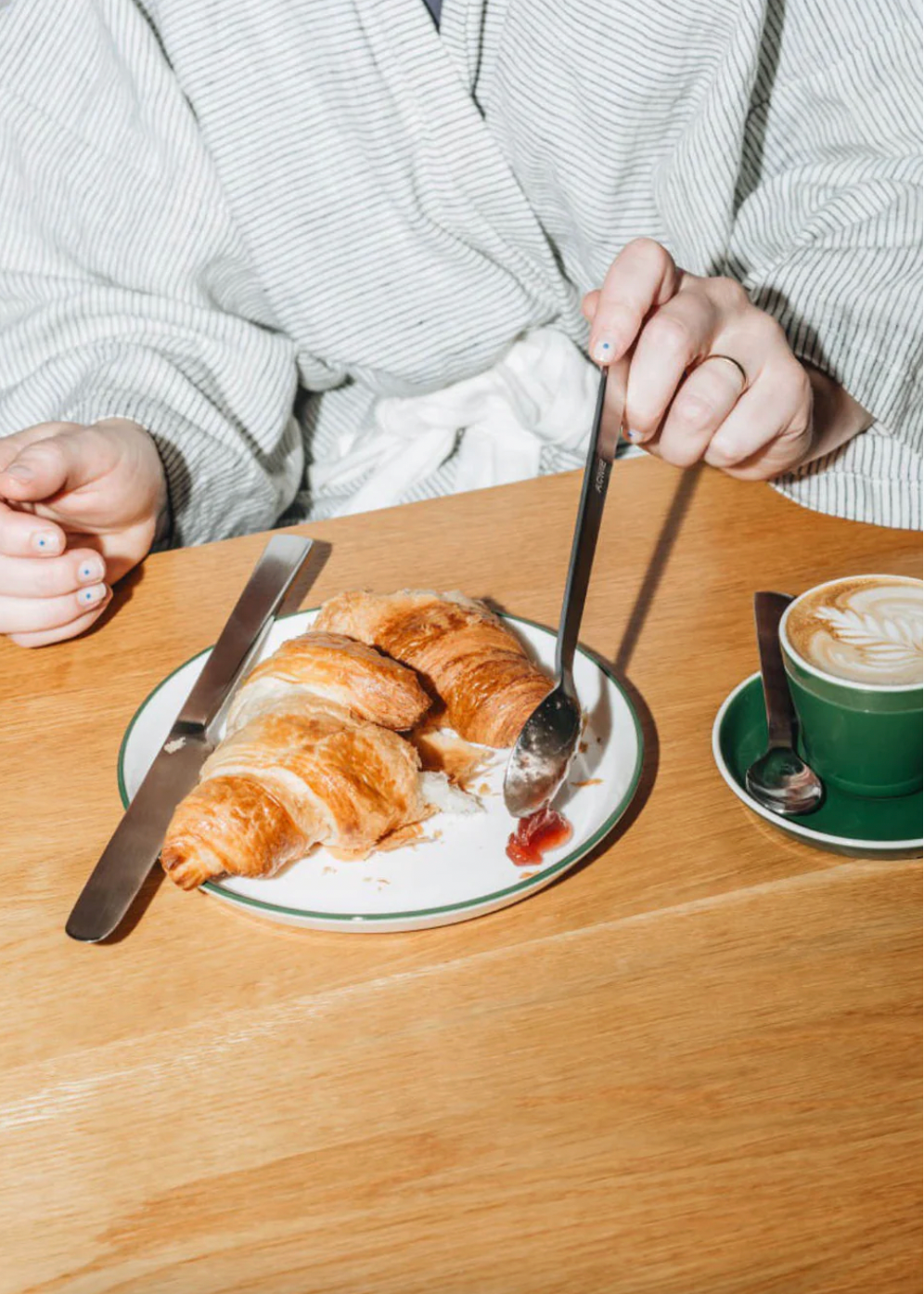 Person sitting at a table with a plate of croissants and a cup of coffee.