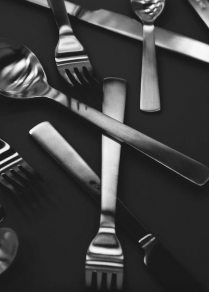 Silverware including forks and knives on a dark surface