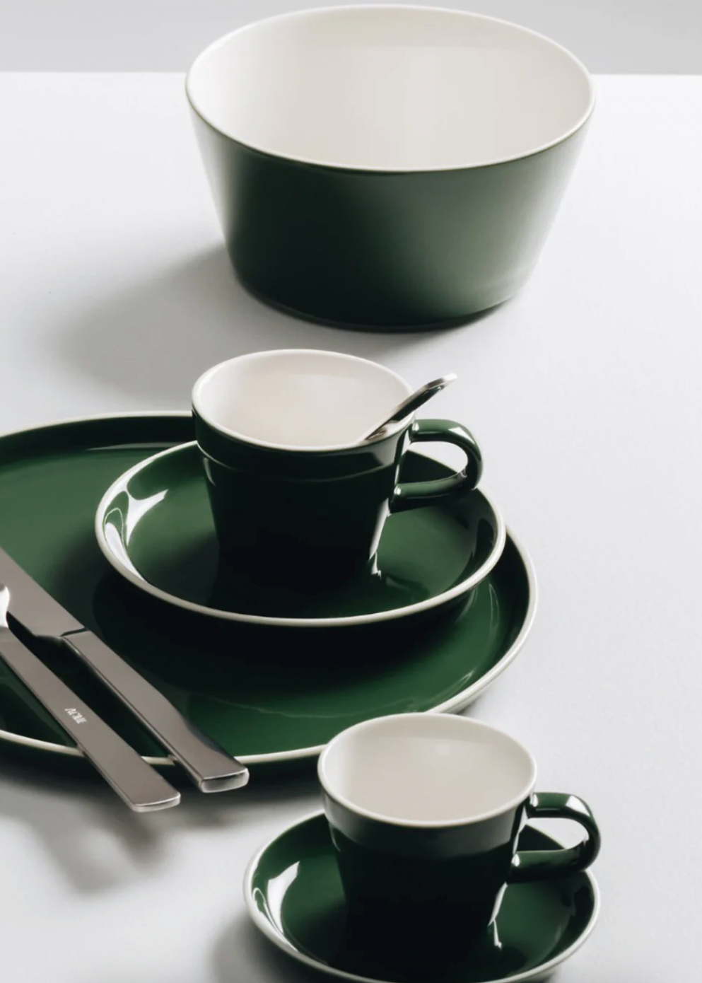 Green and white ceramic tableware set on a white surface