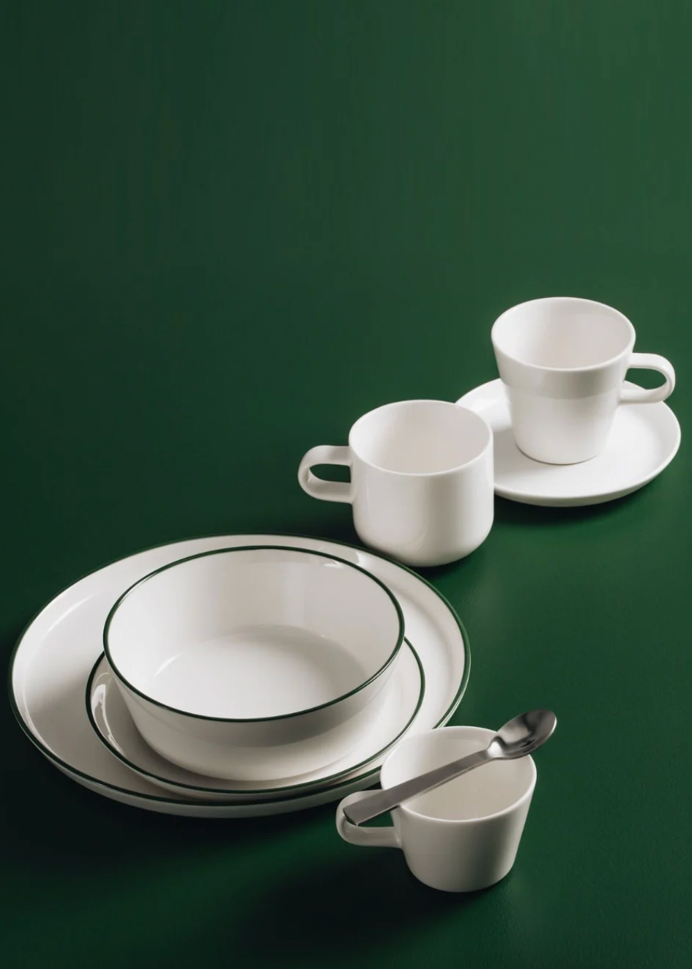 White ceramic tableware set with black rim on a green background