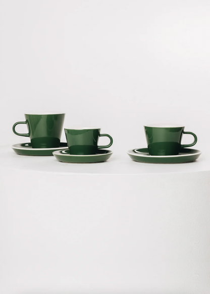 Set of three green ceramic cups with saucers on a white background