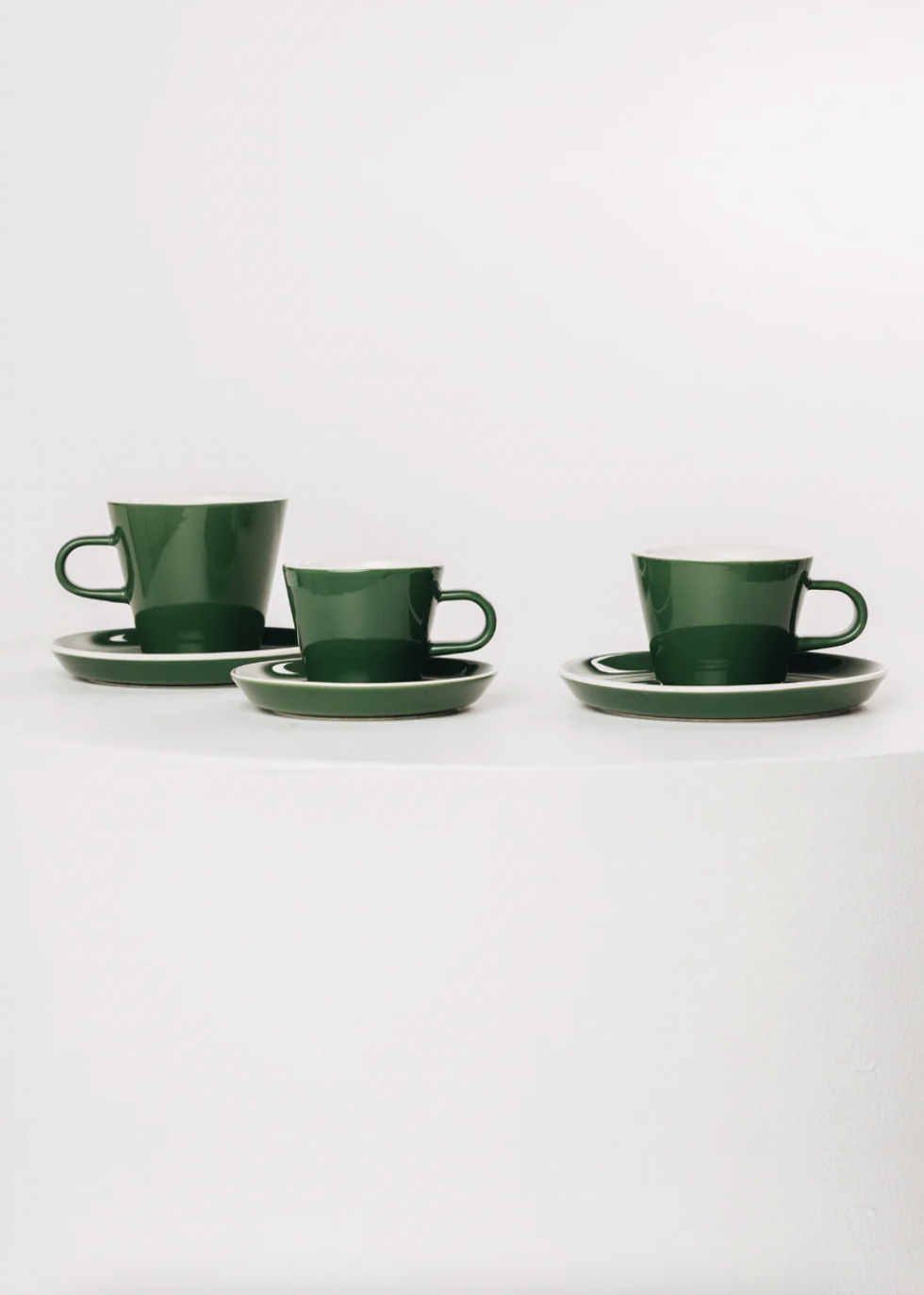 Set of green ceramic cups and saucers on a white background