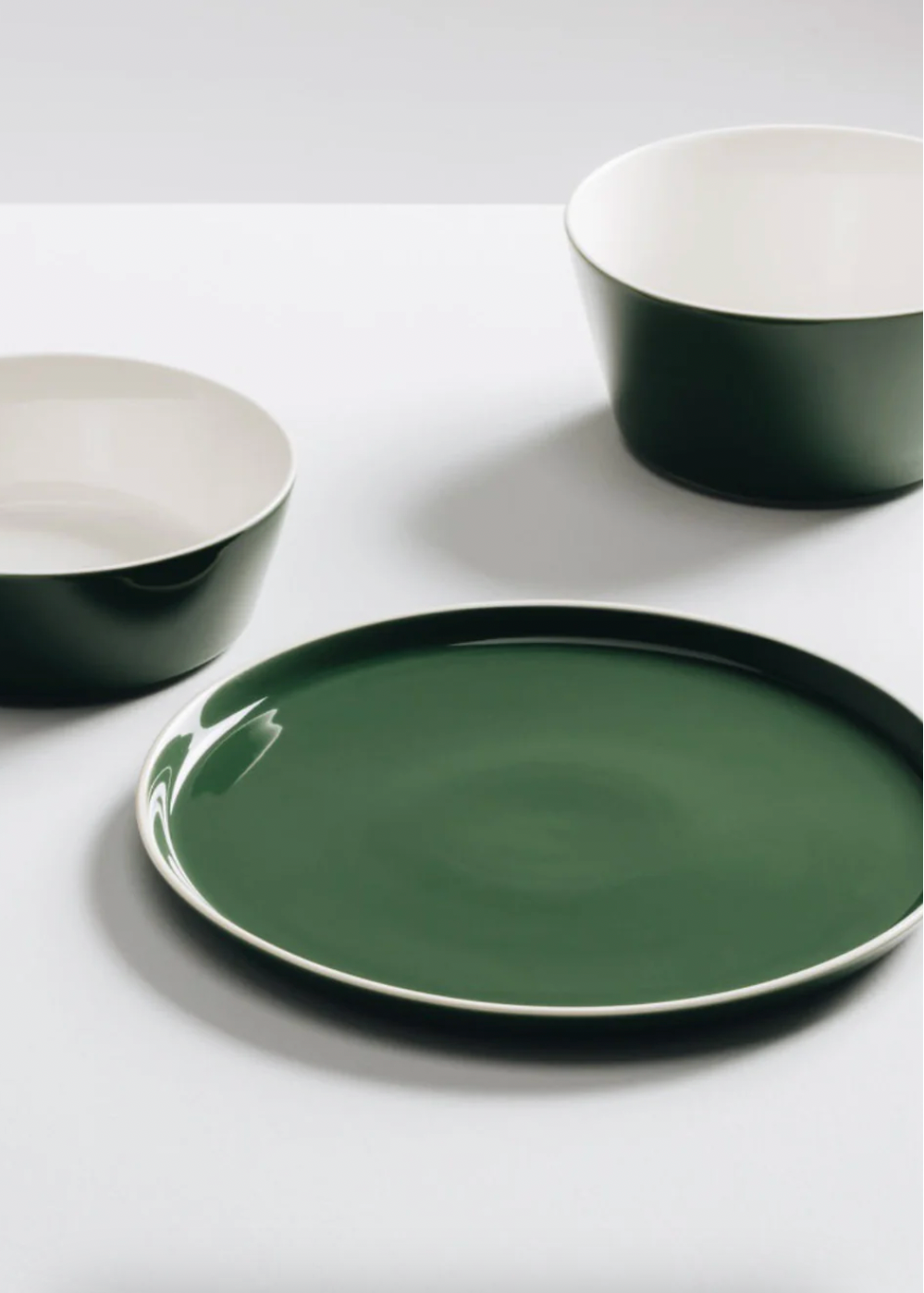 Green ceramic plates and bowls on a white surface