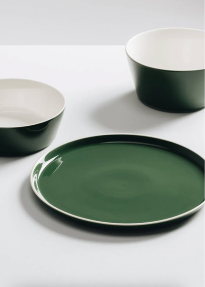 Green ceramic plates and bowls on a white surface