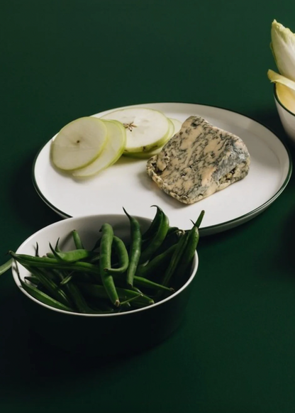 Platter with blue cheese, sliced pears, and green beans on a dark green background