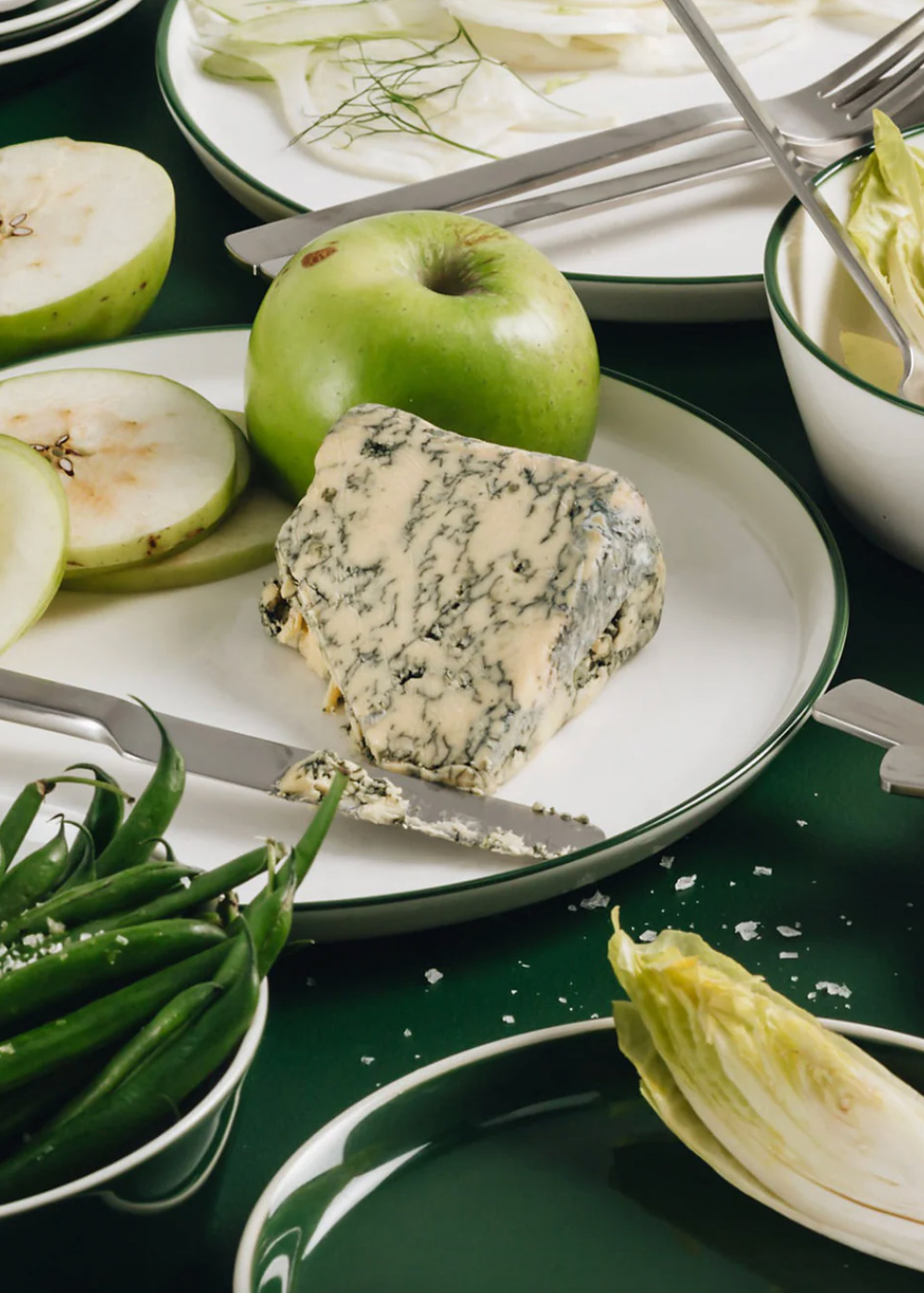 Blue cheese with apples and green beans on a white and green plate