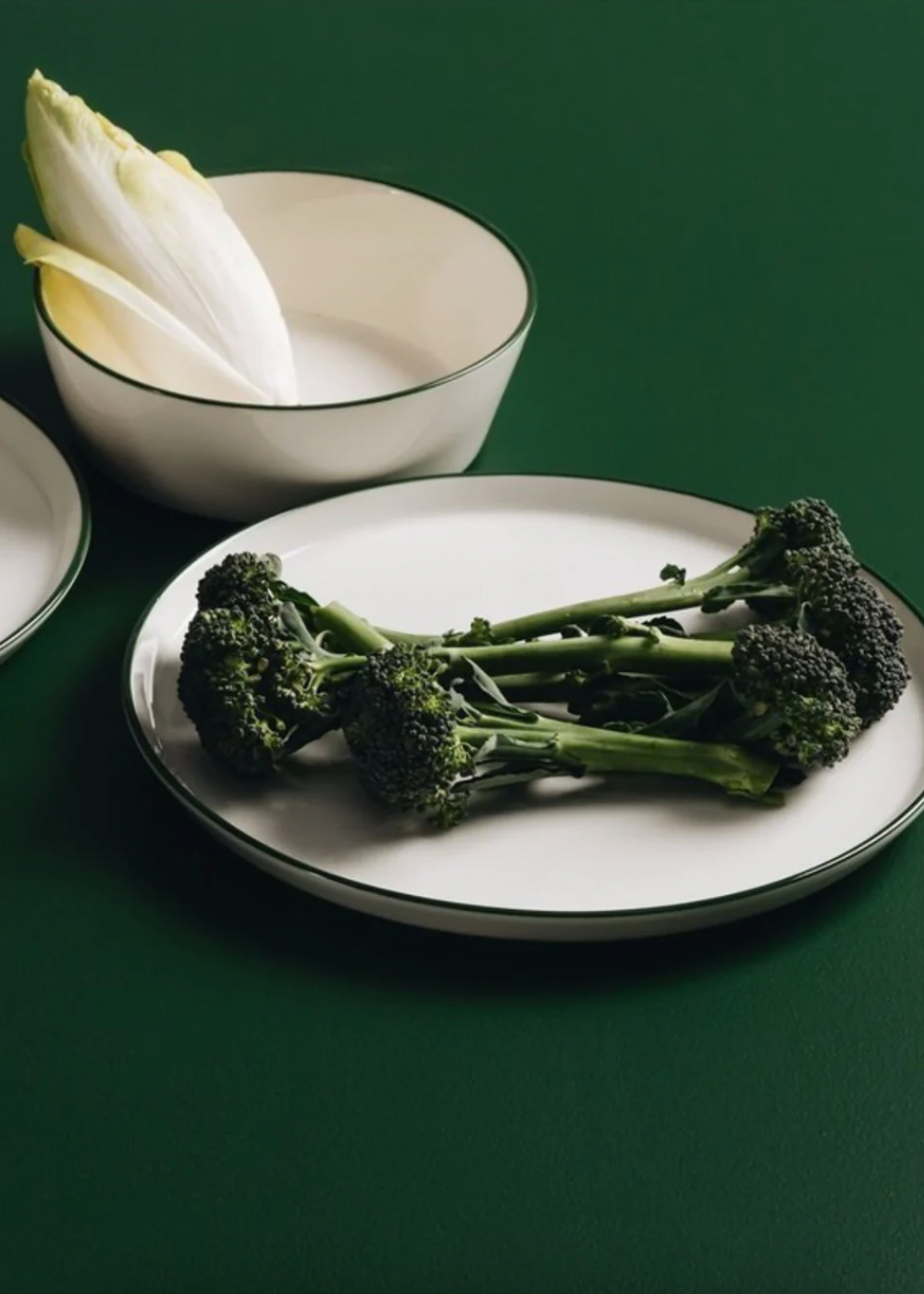 Broccoli on a white plate with a green background