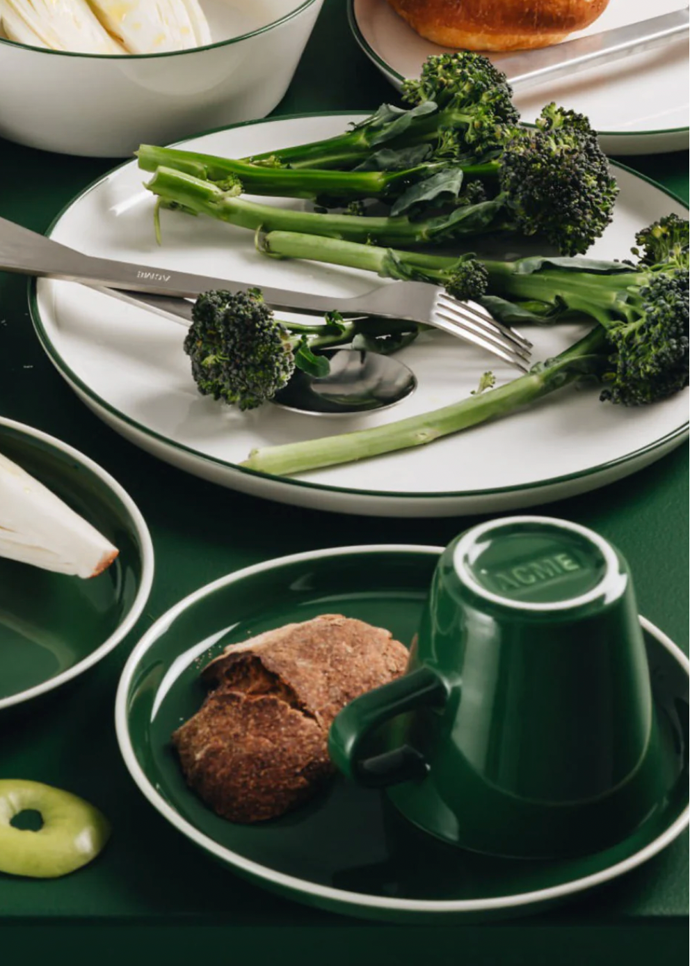Green tableware set with a cup, saucer, and plate on a green surface.