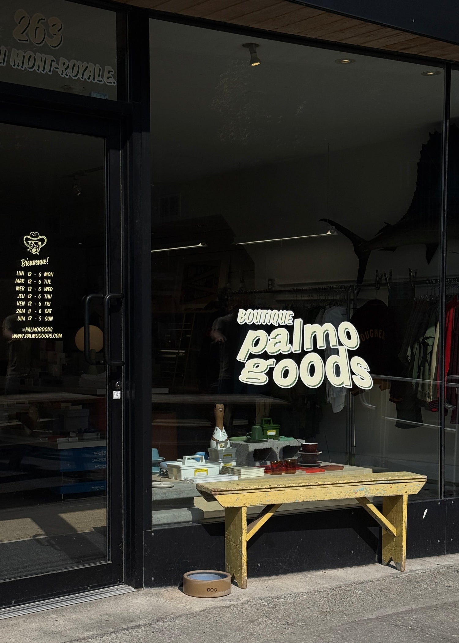 Storefront with 'Boutique Palmo Goods' sign and wooden bench outside