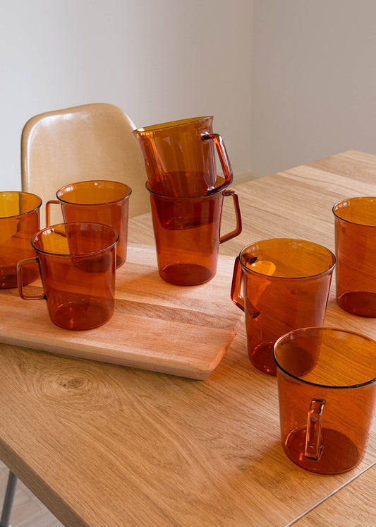 Collection of amber glass mugs and a pitcher on a wooden table.