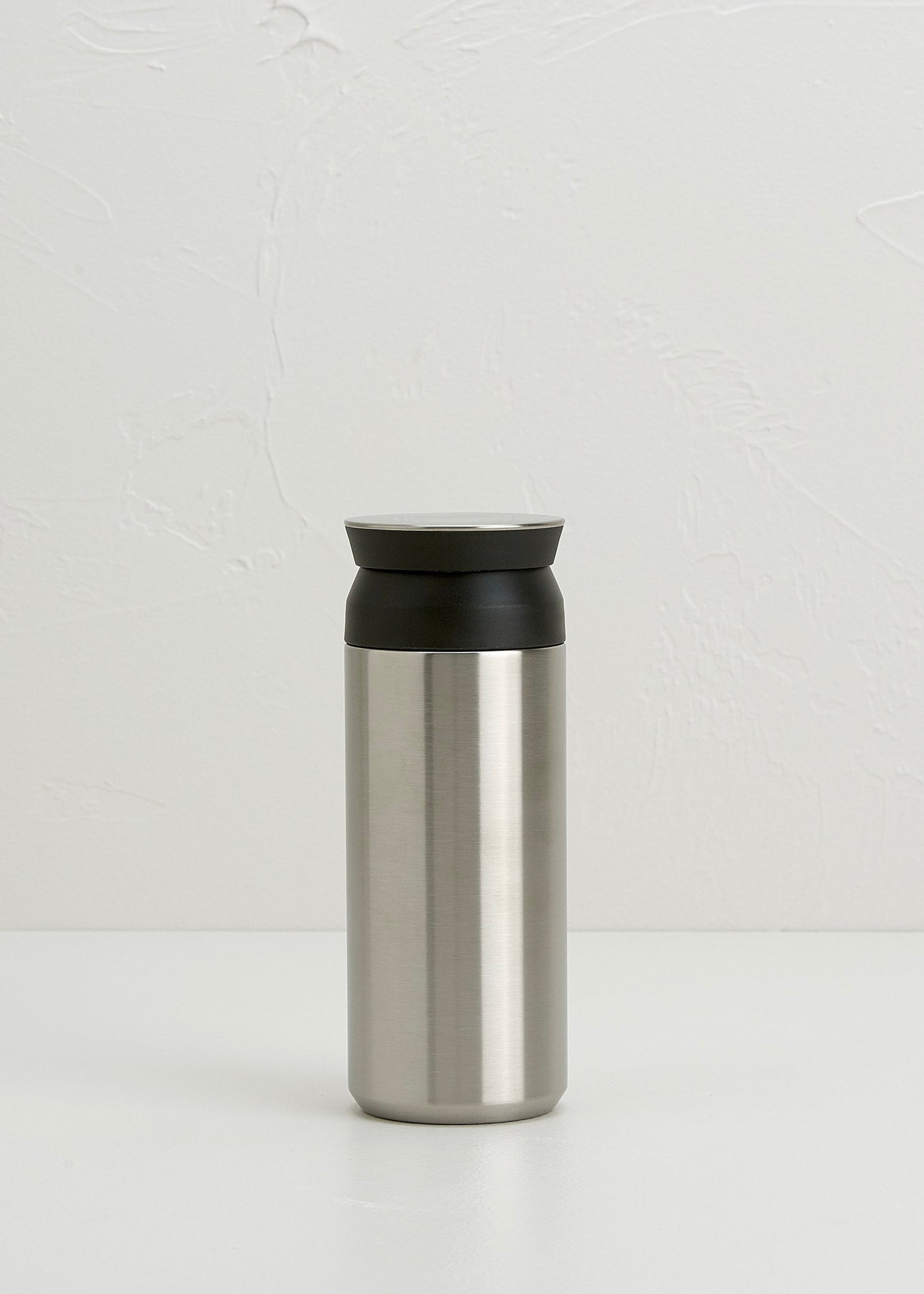 Stainless steel tumbler with black lid on a white background
