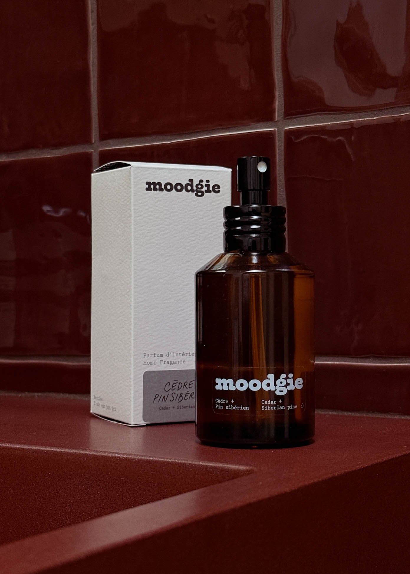 Brown bottle and white box of moodgie product on a red tiled wall.