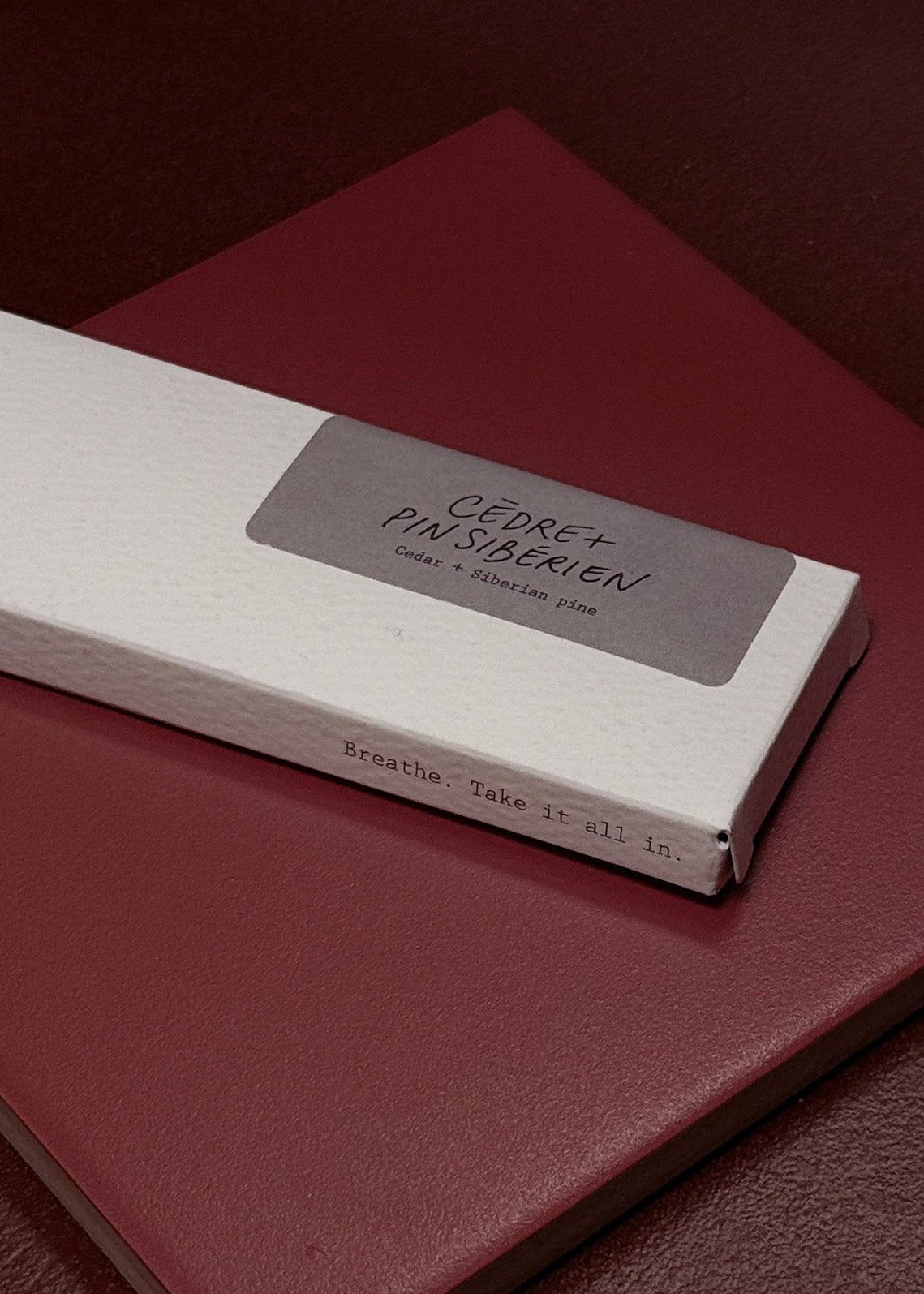 Red tile with a white box of incense on top featuring text saying Cedar and Siberian Pine