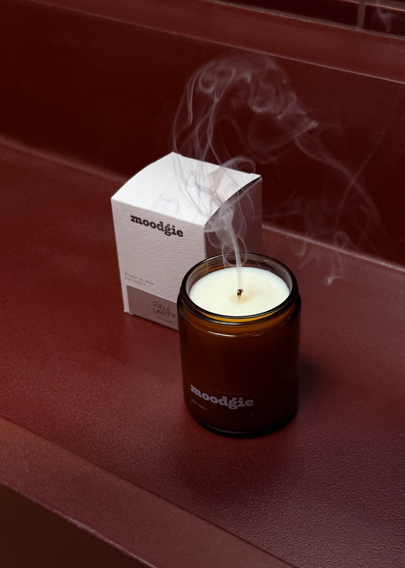 Moodgie candle with smoke emitting from it on a red surface