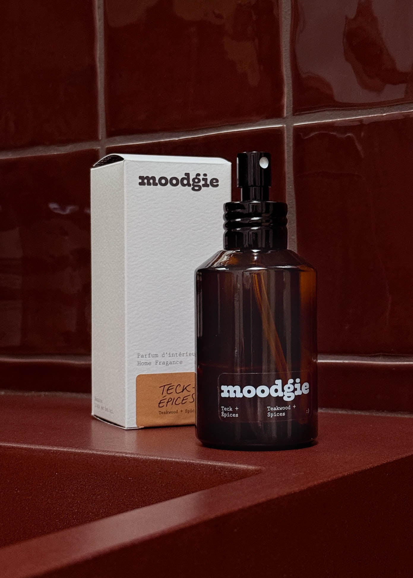 Moodgie perfume bottle and packaging on a red surface with a red tiled wall background