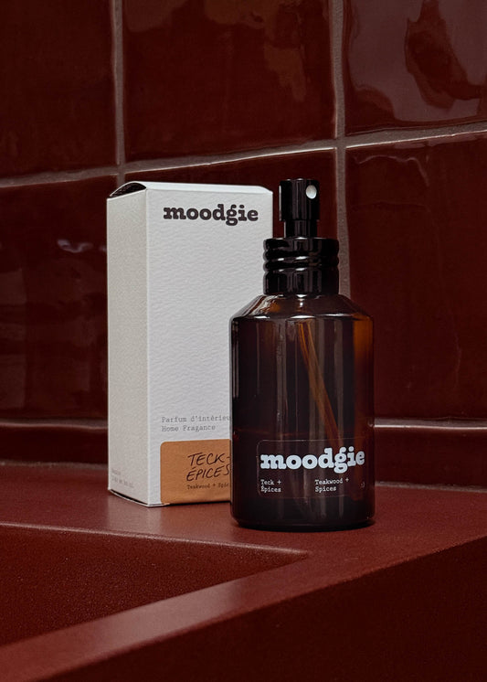 Moodgie perfume bottle and packaging on a red surface with a red tiled wall background