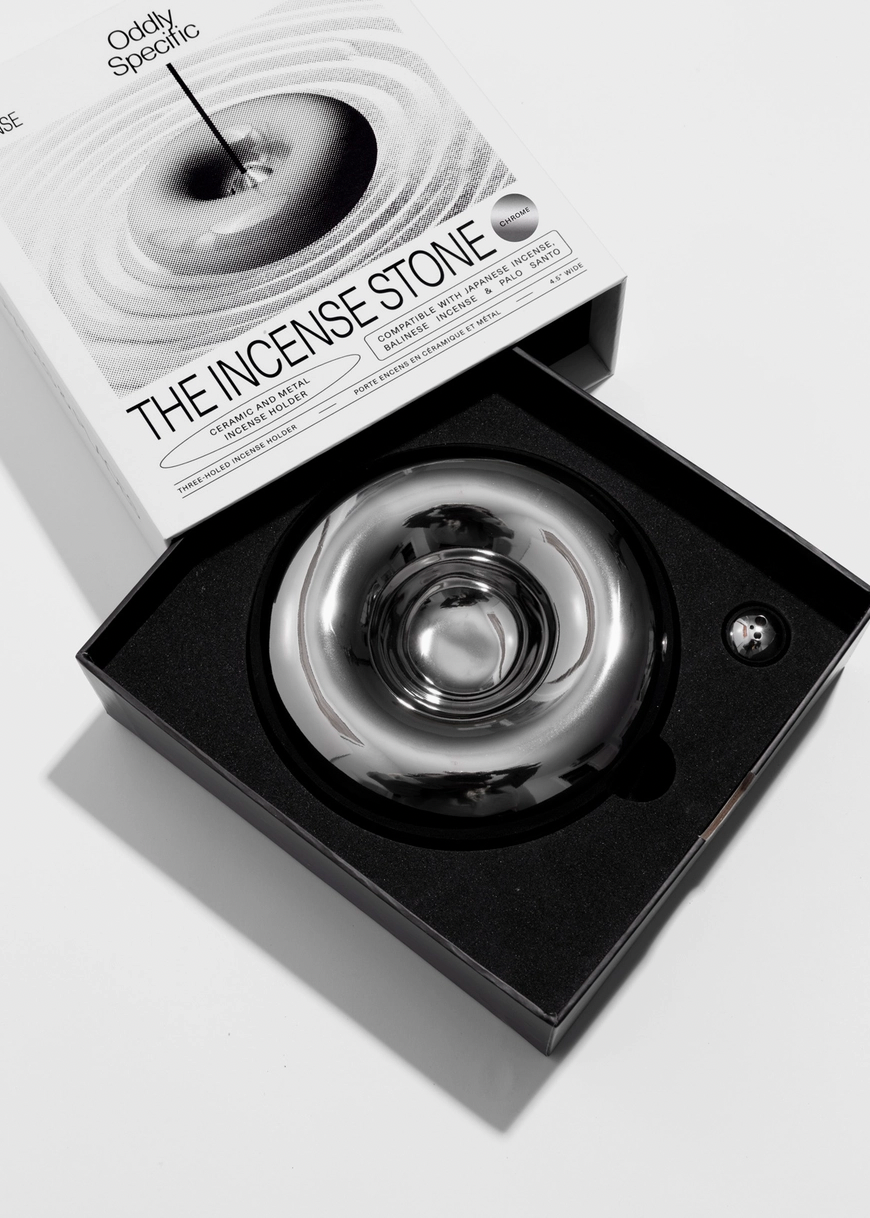 Chrome incense stone in a black box with packaging labeled 'The Incense Stone' on a light background
