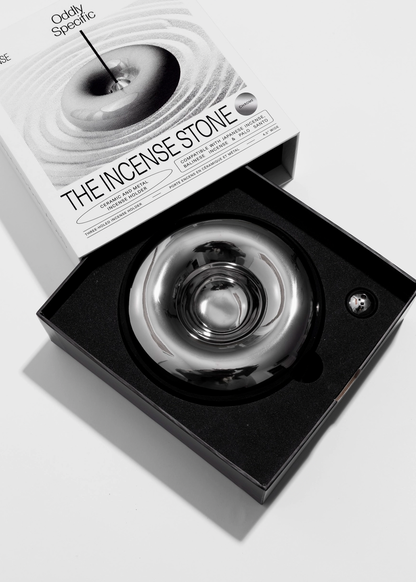 Chrome incense stone in a black box with packaging labeled 'The Incense Stone' on a light background
