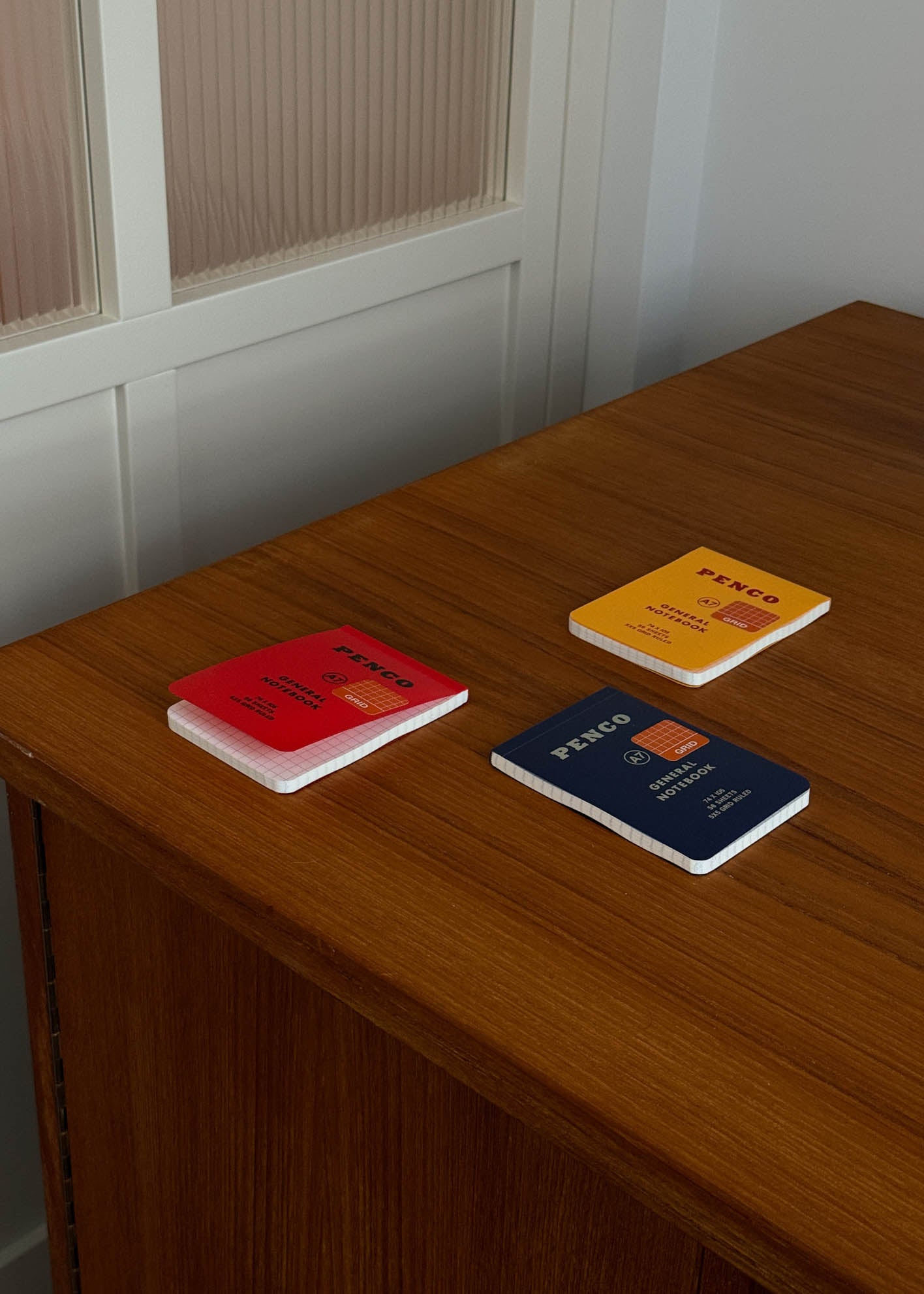 Four colourful A7 notebooks on a wooden surface with a neutral background