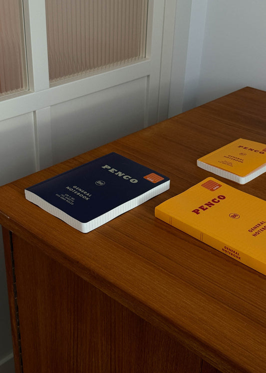Three notebooks with 'Penco' branding on a wooden surface.