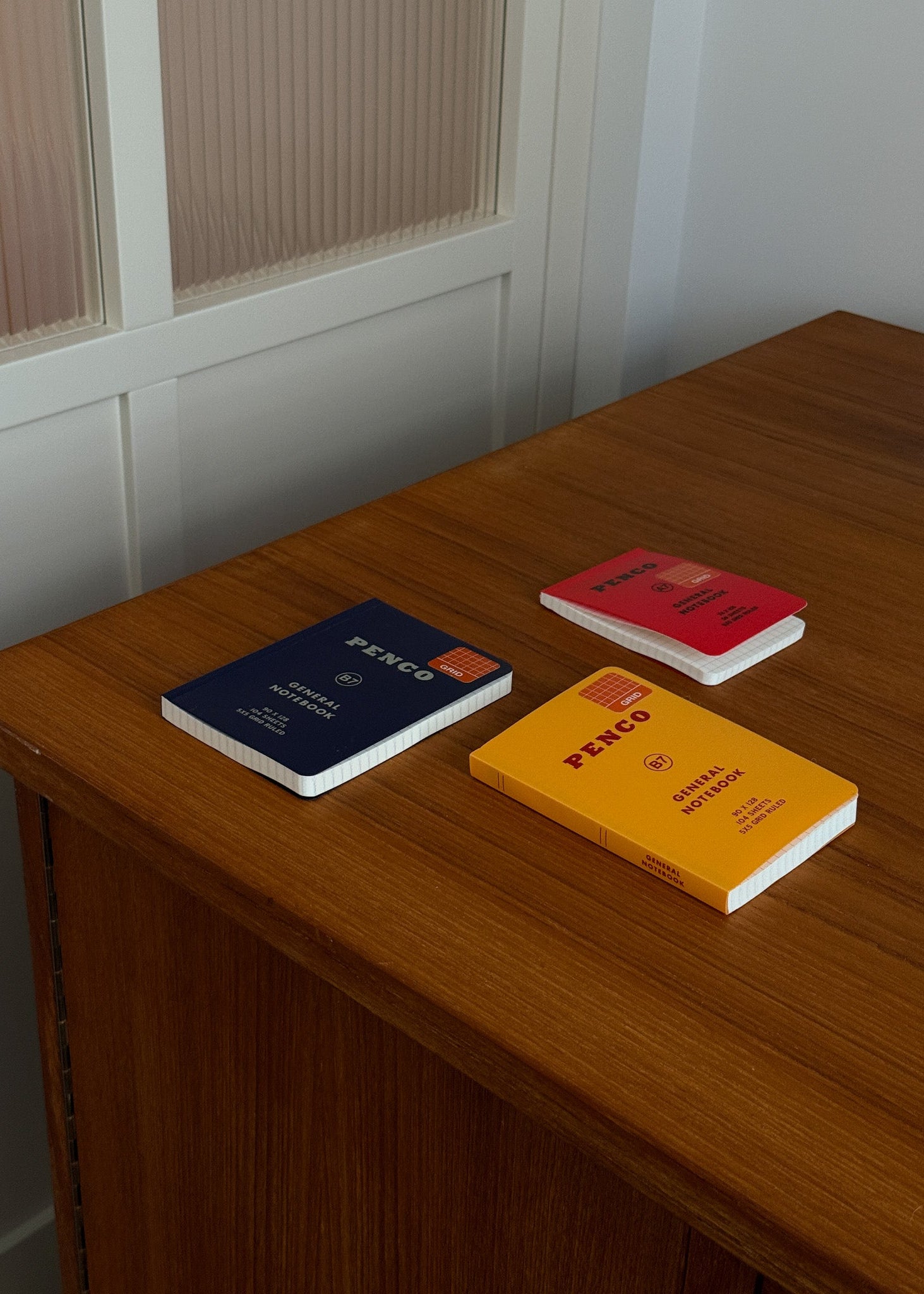 Three notebooks with different colored covers on a wooden surface.