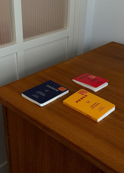 Three notebooks with different colored covers on a wooden surface.