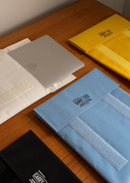 Collection of laptop cases with velcro and visible brand logos on a wooden surface