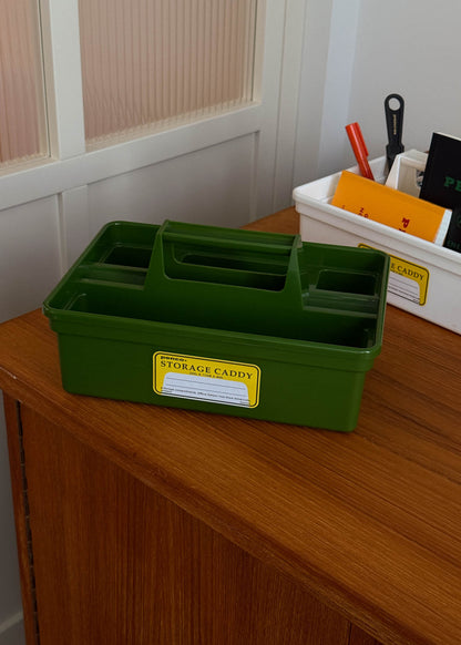Green storage caddy with a yellow label on a wooden surface.