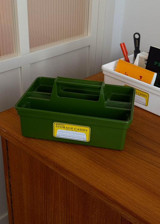 Green storage caddy with a yellow label on a wooden surface.