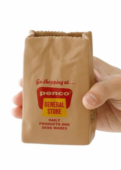 Hand holding a small cardboard box with 'Penco General Store' branding on a white background