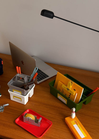 Desk with storage containers, a laptop, and a lamp in a minimalistic room.