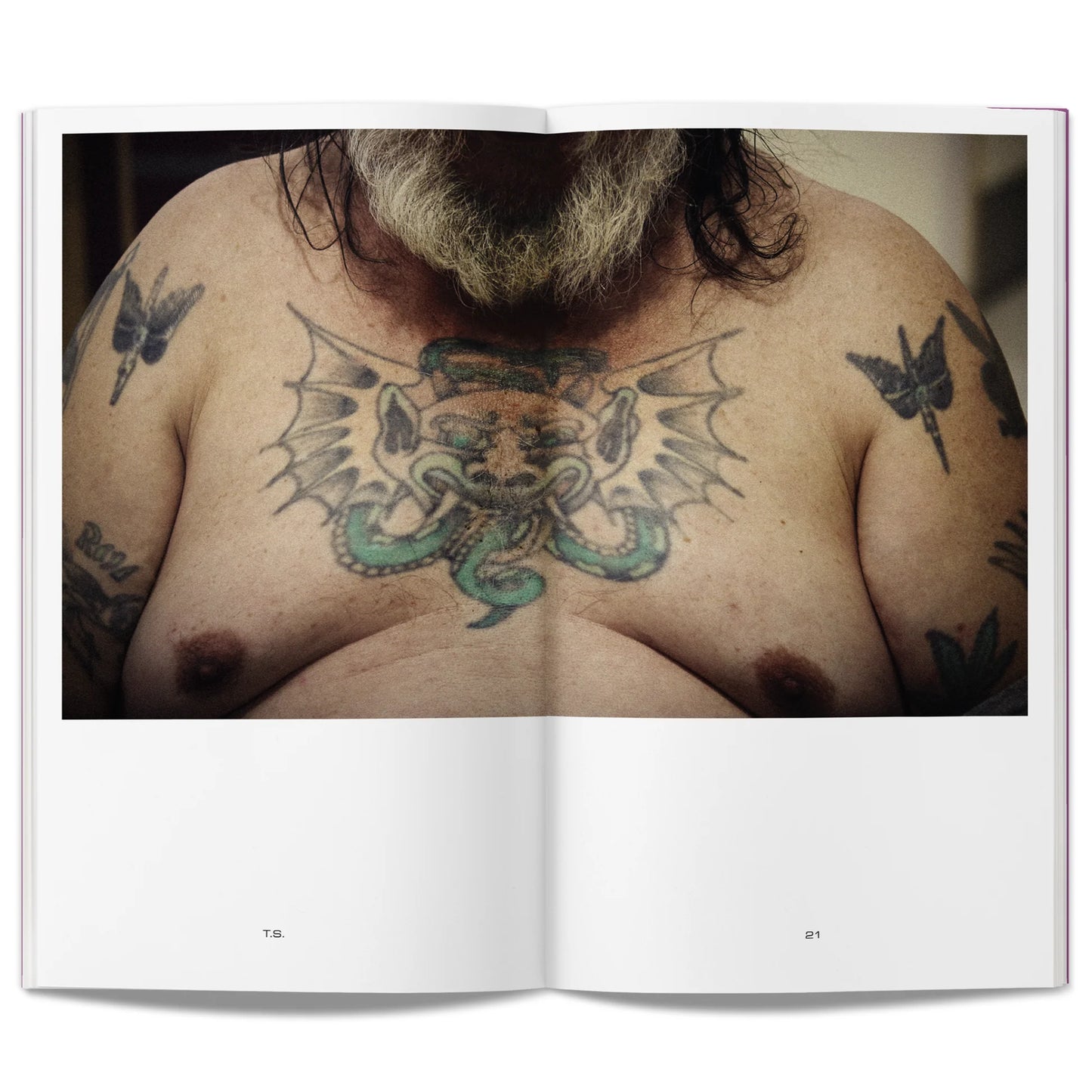 Open book showing a photograph of a person with tattoos on their chest and shoulders.