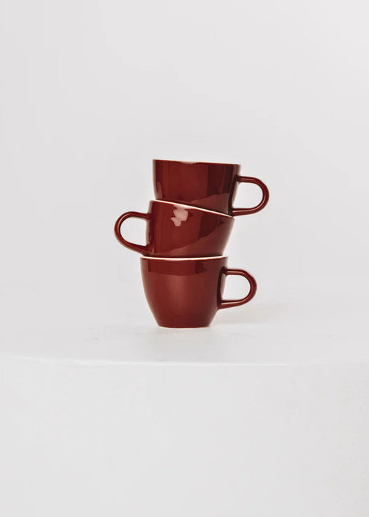 Stack of three red ceramic cups on a white background